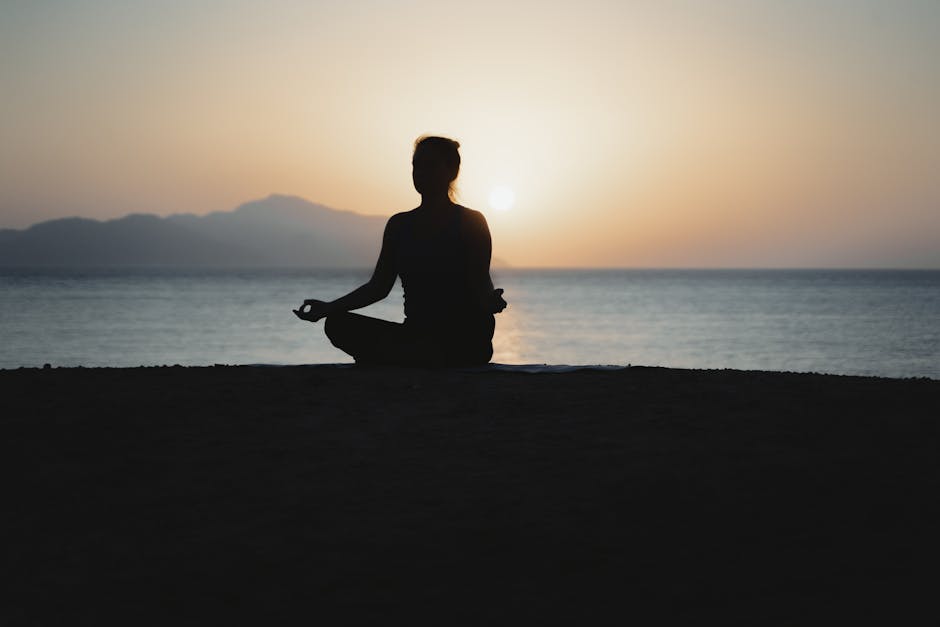 Woman practicing yoga on a balcony with a sunset view.